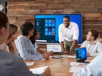 Five people in meeting room with windows collaboration display from Sharp