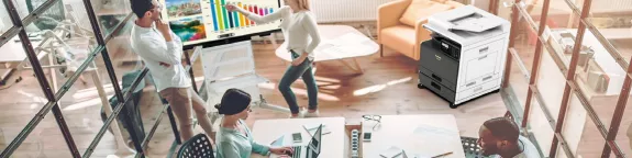 Four people in an office at desks and using an interactive display