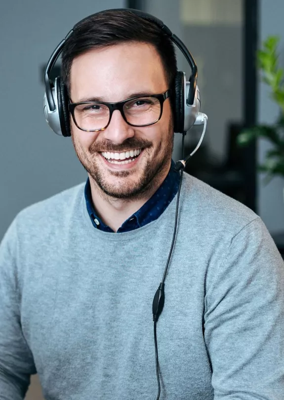 A man wearing a headset whilst using a computer